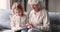 Little girl learning reading book with happy middle aged grandmother.