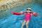 Little girl learning to swim with pool noodle