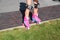 Little girl learns riding pink four-wheeled roller skates on the grass, knee pads, legs, close-up