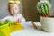 Little girl learns to cut out of paper. Teaching children applications at home. child holds baby scissors in his hands