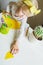 Little girl learns to cut out of paper. Teaching children applications at home. child holds baby scissors in his hands