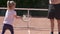 A little girl learns to play tennis on a dirt court in the summer