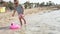 Little girl lets a toy pink flamingo swim in the sea.