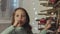 Little girl licking candy standing at the wooden Christmas tree