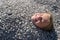 A little girl lies on the beach under the pebbles. A playful baby is buried in the pebbles on the beach, only her head is visible.