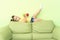 Little girl lies on a green sofa holding his leg in his hands an apple and a tomato