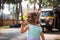 A little girl with light curly hair - with an Indian auto rickshaw in the background.