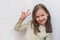 Little girl in a light sweater shows a victory sign with her hand