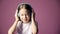 little girl listens to music through headphones, a child dances to music on a pink background