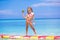 Little girl with lollipop have fun on surfboard in