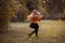 Little girl with long hair in red sweater and black skirt waving around at the autumn glade. Copy space