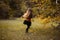 Little girl with long hair in red sweater and black skirt waving around at the autumn glade. Copy space