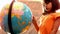 Little girl looking at globe in classroom