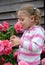The little girl looks at the blossoming roses
