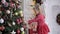 A little girl looks at a large Christmas tree with interest.
