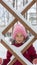 Little girl looks through the snow coated latticework fence