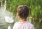 Little girl looks on a swan standing at water