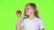 Little girl looks at a tomato, admires it and shows a thumbs up. Green screen. Slow motion