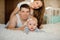 Little girl lying on the bed among her smiling parents