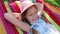 A little girl lying in a hammock on the street in the park. a little sweet girl in a hat lying on a bright hammock.