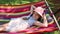 A little girl lying in a hammock on the street in the park. a little sweet girl in a hat lying on a bright hammock. girl in the pa
