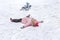 A little girl is lying in snow after falling from his snowmobile, sledge. Childrens going sledding