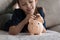 Little girl lying on sofa put coin into piggy bank