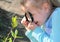 Little girl with a magnifying glass in her hand investigate  details of nature . Happy looks at the young spring, Springtime