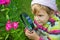 Little Girl with magnifying glass looks at flower
