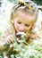 Little girl with magnifying glass looks at flower