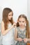 Little girl makes ponytails of her younger sister