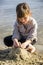 A little girl makes a sand sculture of cat