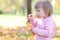 Little girl making bubble blower on the autumn forest