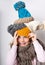 Little girl with many warm winter hats in different colors with text copy space looking at the camera