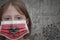 Little girl in medical mask with flag of albania stands near the old vintage wall with text coronavirus, covid, and virus picture