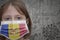 Little girl in medical mask with flag of andorra stands near the old vintage wall with text coronavirus, covid, and virus picture