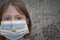 Little girl in medical mask with flag of argentina stands near the old vintage wall with text coronavirus, covid, and virus