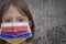 Little girl in medical mask with flag of armenia stands near the old vintage wall with text coronavirus, covid, and virus picture