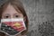 Little girl in medical mask with flag of Papua New Guinea stands near the old vintage wall with text coronavirus, covid, and virus