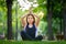 A little girl meditates in the park in the lotus position the girl does yoga raised her hands up and folded her palms