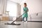 Little girl mopping floor in living room at home