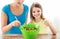 Little girl with mother mixing salad in kitchen