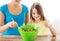 Little girl with mother mixing salad in kitchen