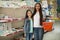 Little girl and mother near shelves with school stationery