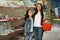 Little girl and mother near shelves with school stationery