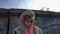 Little girl with muddy face standing at barbed wire, war child in refugee camp