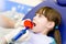 little girl with open mouth receiving dental filling drying procedure.