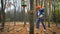 Little girl in orange helmet and protective gear on rope-way in autumn  forest. smiling child engaged climbing rope park.