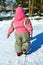 Little girl in overall Pulling sledges in winter