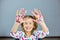 Little girl with painted colorful watercolor hands up, child sitting at the table and drawing,